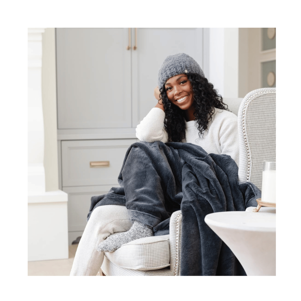 Woman sitting comfortably with Saranoni Oversized Blanket, highlighting soft microfiber fabric and relaxed lifestyle vibe.