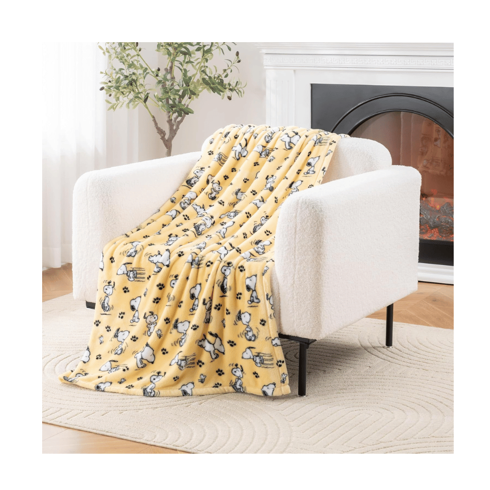 Berkshire VelvetLoft Snoopy plush throw blanket featuring playful Peanuts design on a cozy bed