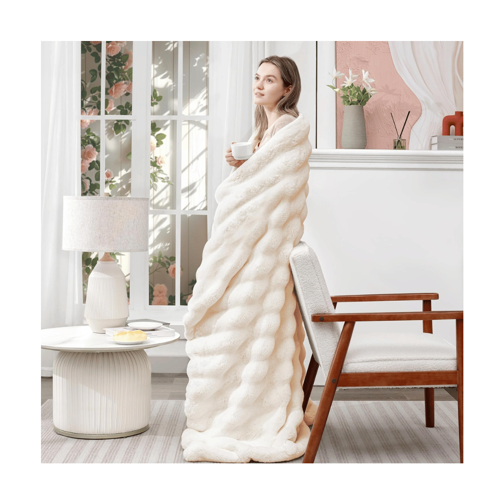 Woman wrapped in Touchat Faux Rabbit Blanket standing in bright modern room, showing thick faux fur design.