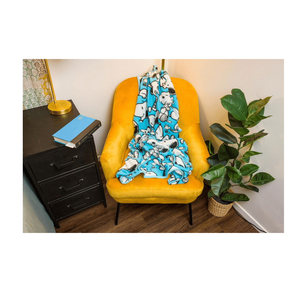 Peanuts Snoopy multi-pose fleece blanket displayed on couch with cozy texture