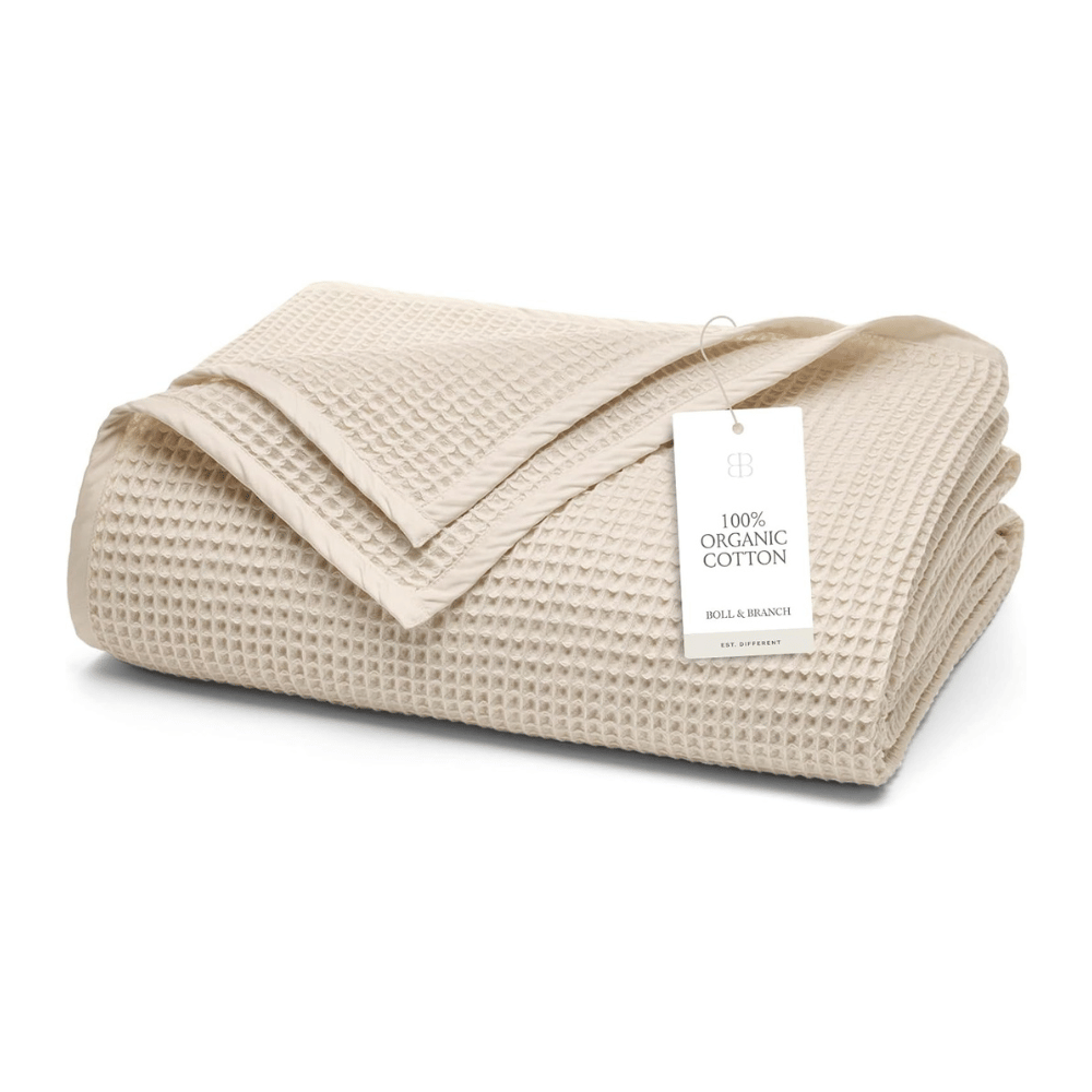 Folded Boll & Branch Waffle Bed Blanket made from organic cotton, featuring waffle weave pattern and brand tag.