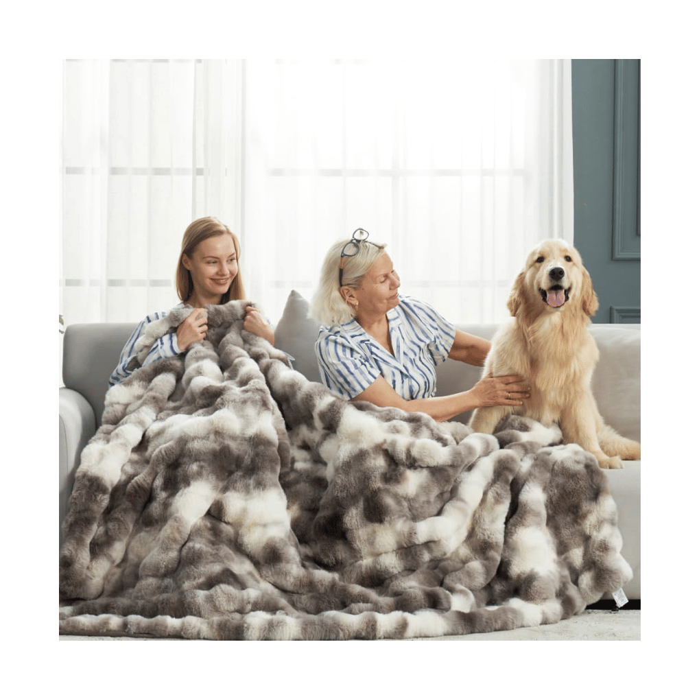 Two women and a dog under Cozy Bliss Faux Fur Blanket, showing cozy faux fur design and living room setting.