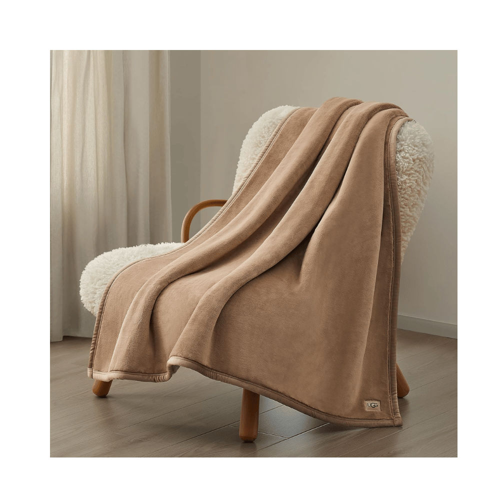 UGG Salt Creek Throw Blanket draped over armchair in softly lit bedroom (Credit: MyRadiantSleep.com)